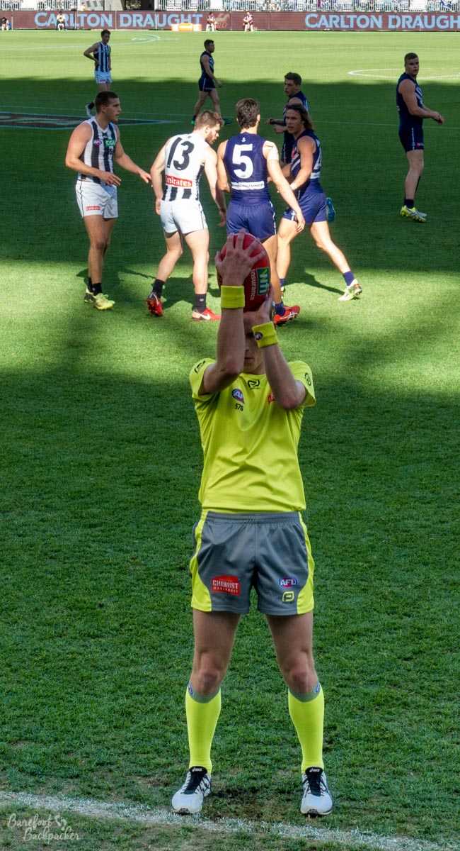 Umpire throwing in the ball during an AFL game at Optus Stadium, Perth