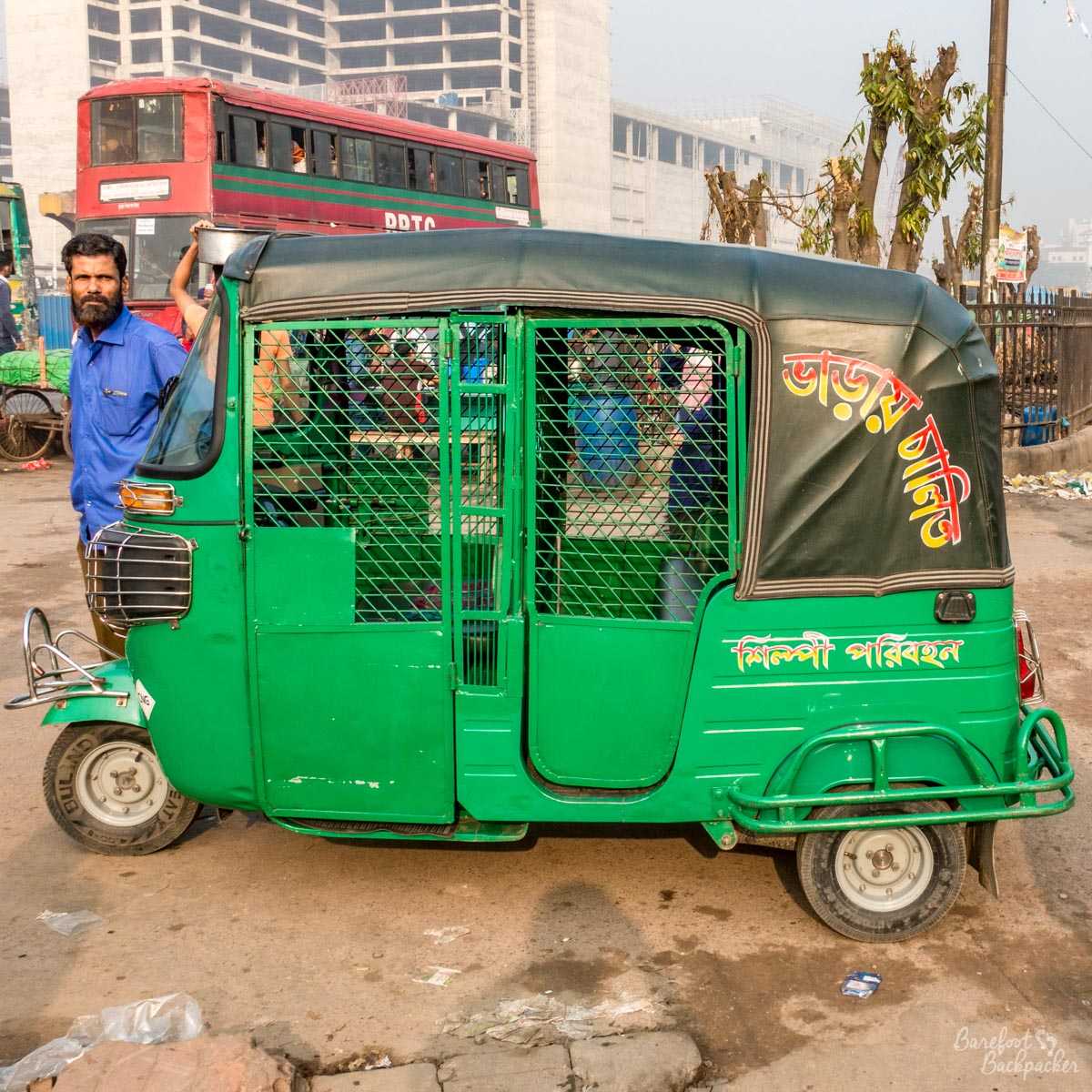 A CNG (gas-powered auto-rickshaw) in the parking bay at the Airport railway station in Dhaka, Bangladesh. It's basically a metal cage on wheels. The standard method of travel across the city. Scary af!