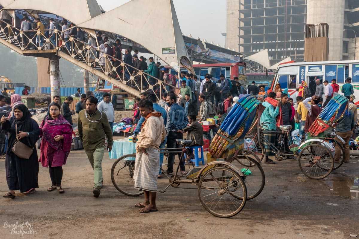 Street scene near Dhaka Airport Railway Station, with crowded footbridge, and a mass of rickshaws and stalls.