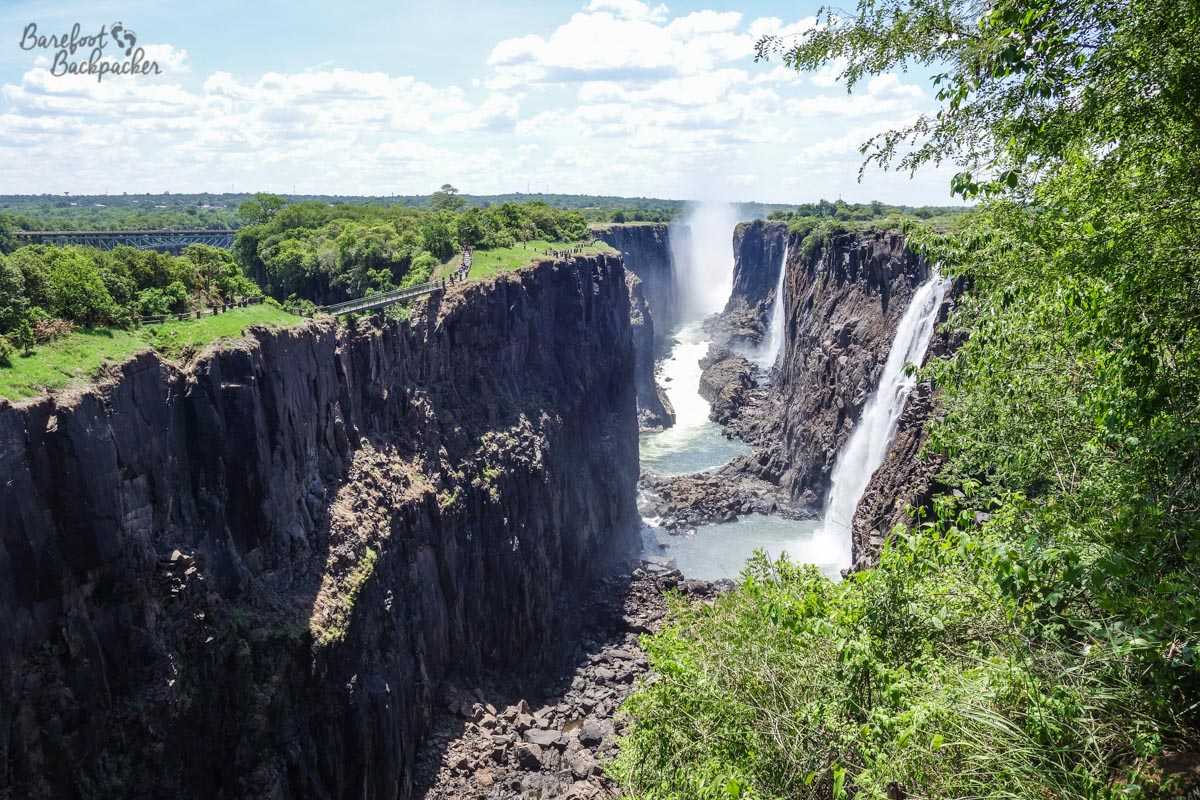 Looking across Victoria Falls – the water cascades into a small chasm either side of sheer rock cliffs. Lots of spray.