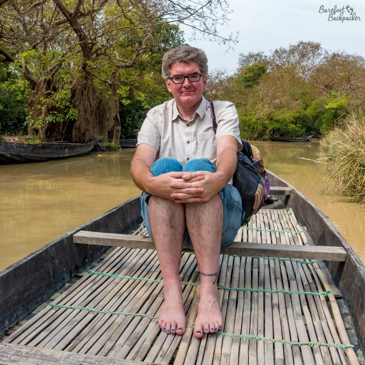 The Barefoot Backpacker, sitting on a canoe/boat in the Ratargul swamp forest