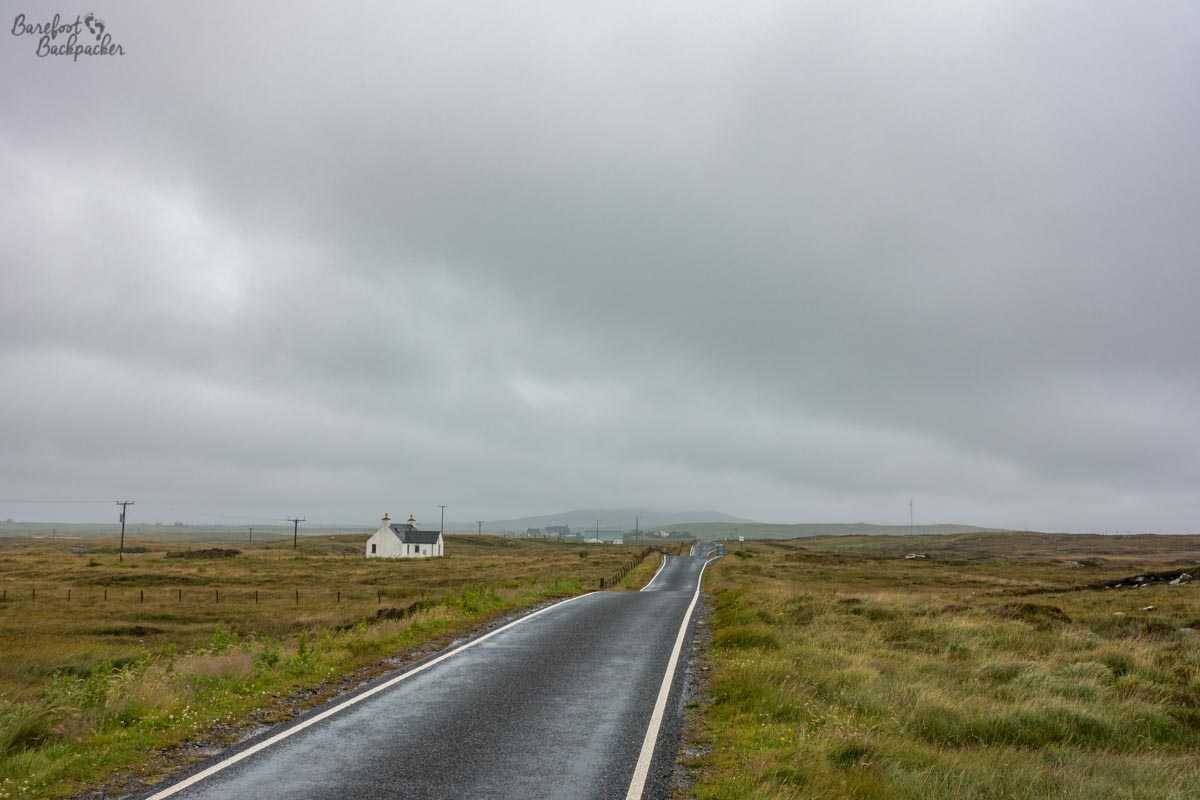 A lonely house by the side of the road on North Uist, under a grey, leaden, heavy sky.