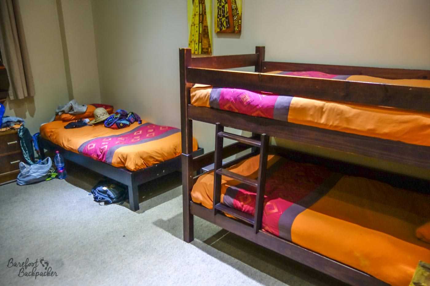 The minimalist but colourful scheme extended to the dorm rooms; here a bunk and a simple single bed lie along the wall, Orange is the dominant hue.
