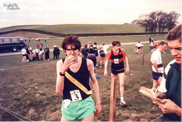 Old picture; teenage boys at the end of a cross-country race, filtering up a 'funnel' of fencing to the timing officials.