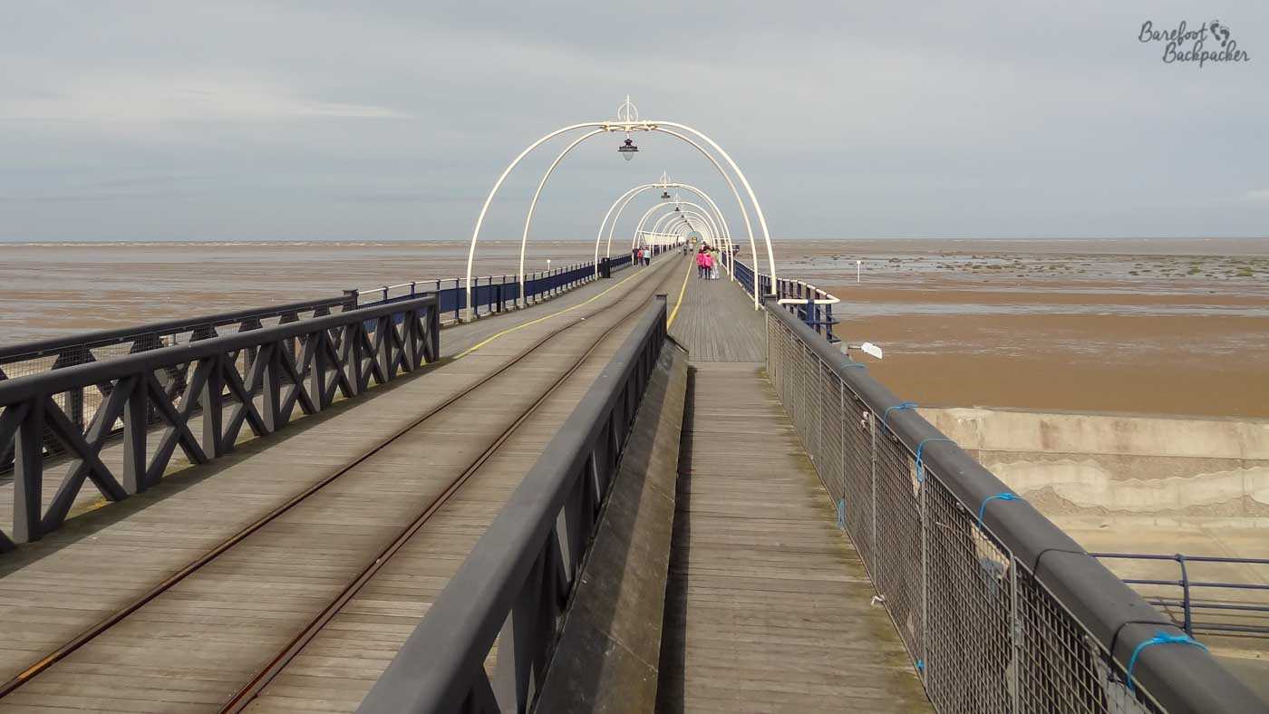 Southport pier, a rail line and a footpath under a couple of metal arches, disappears into the distance over the sand
