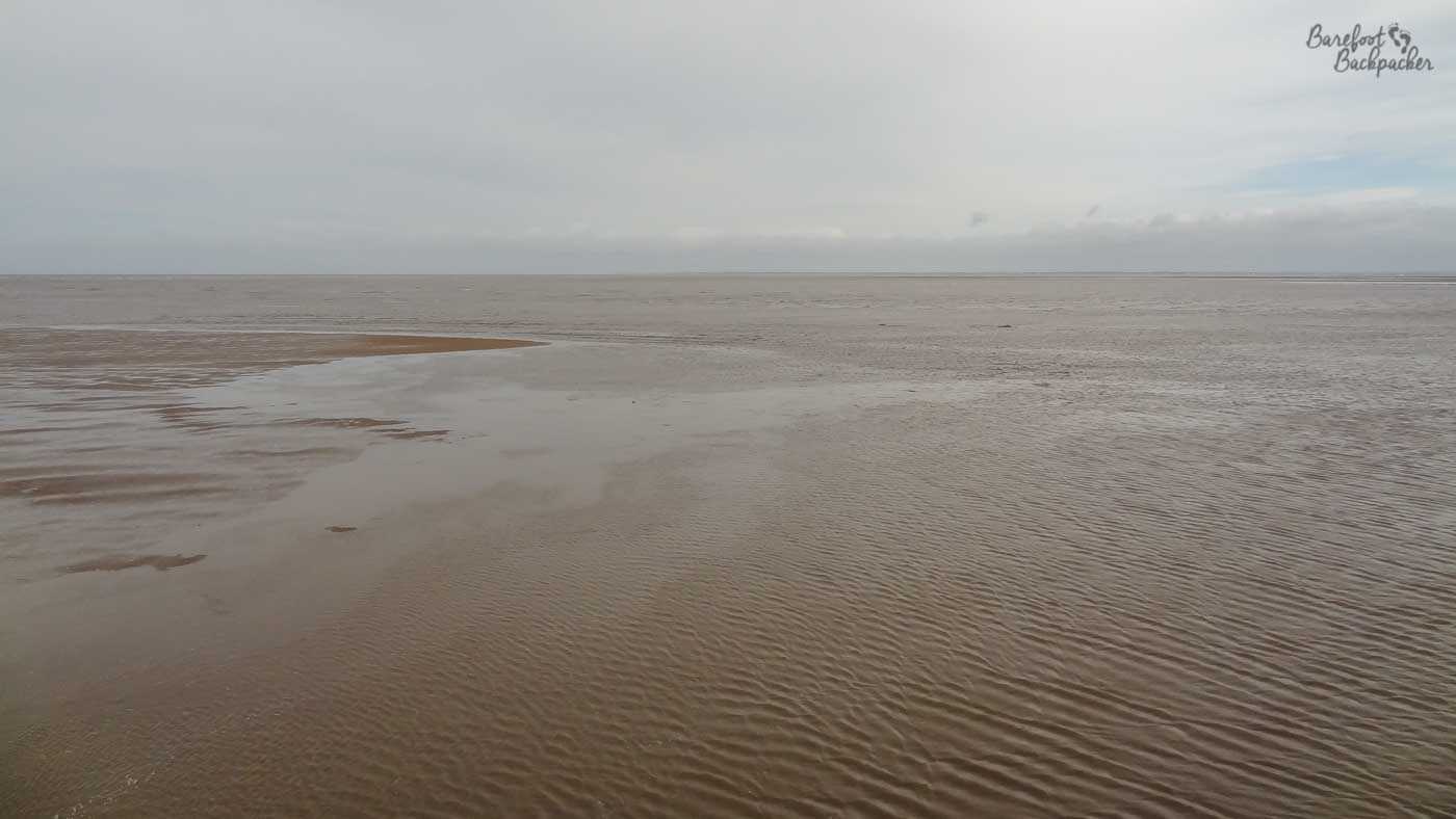 Southport beachfront – wet sand under a cloudy sky. Featureless. Also, the sea can't be seen.