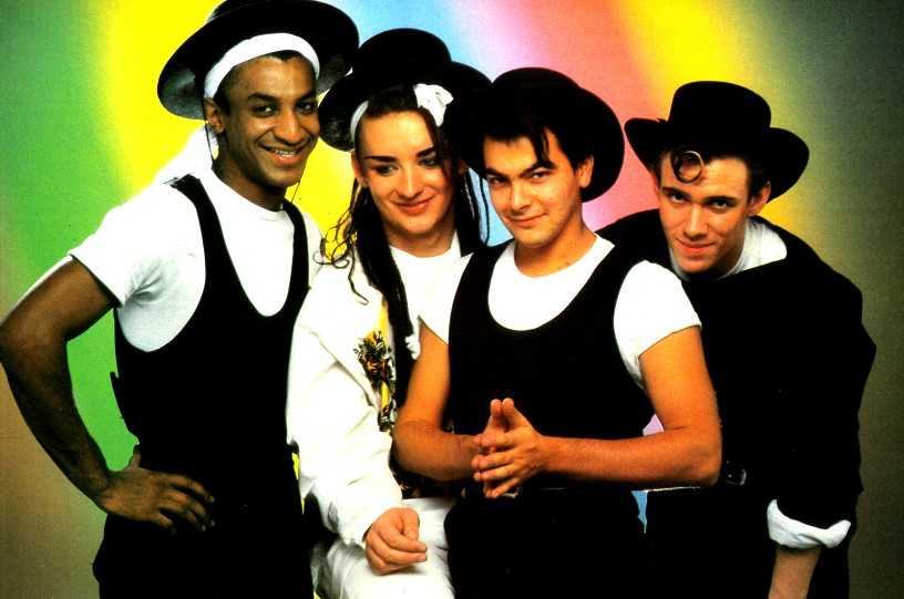 Publicity shot of the 80s pop band Culture Club, in front of a bright rainbow-vibe background.