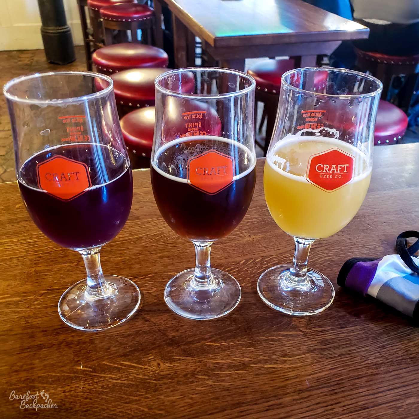 Three small glasses of beer on a pub table.
