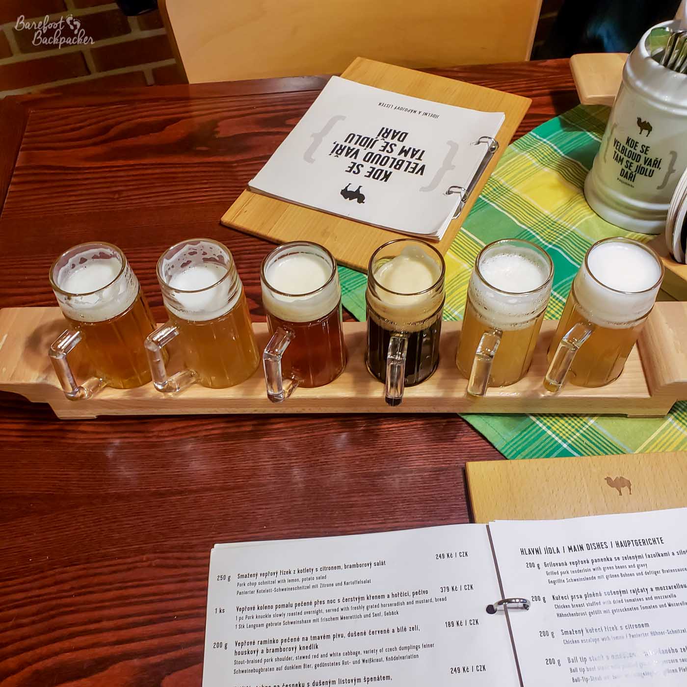 A flight of six beers on a table in a pub.