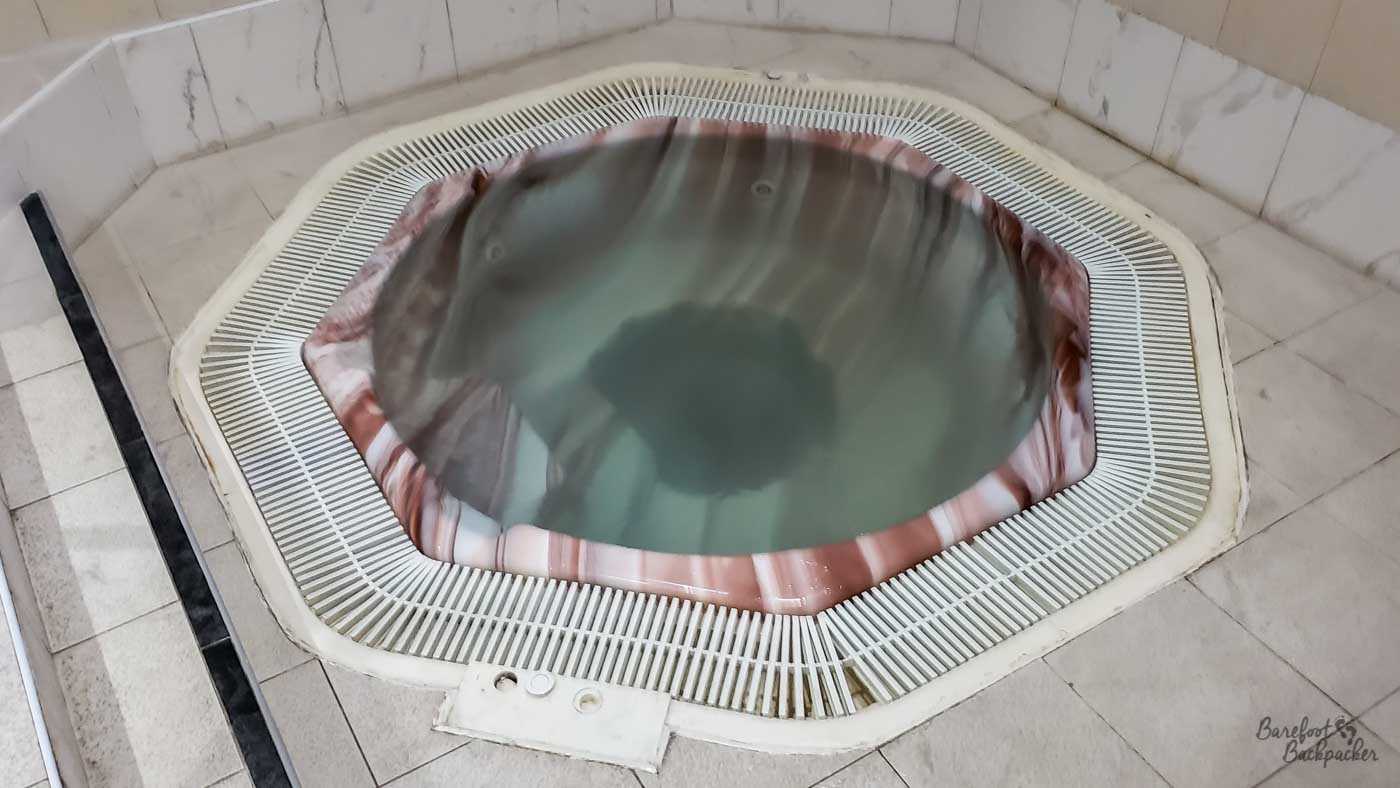 An octagonal pool of water is set in the floor. The floor and surrounds are tiled.