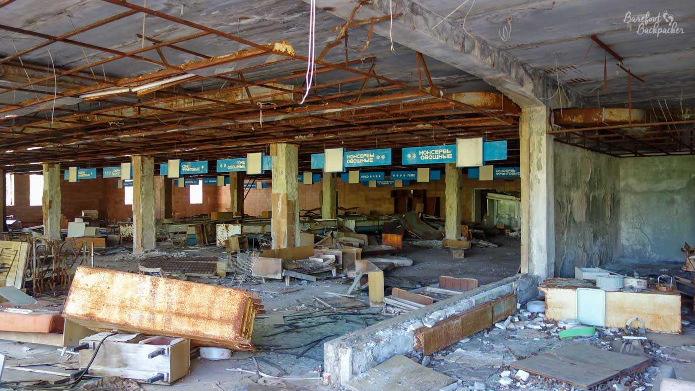 Inside what used to be a supermarket in Pripyat. The shelving and its attachments are scattered on the floor but the signs hanging from the ceiling that tell you what each aisle was are still there
