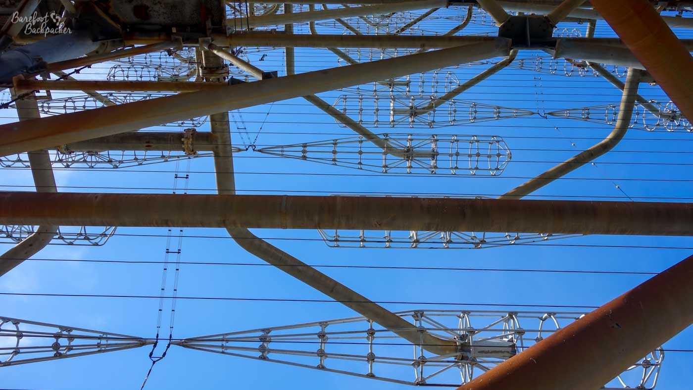 Picture from below of a large radar/transmitter frame, mostly consisting of long metal pipes and many metal connectors that resemble the skeleton of a baseball bat.