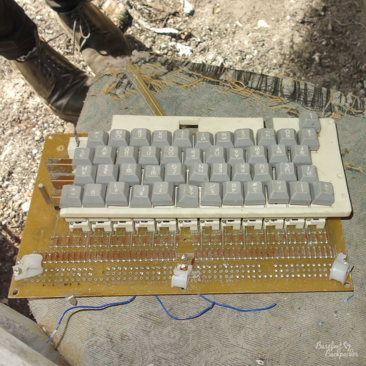 A broken computer keyboard with cyrillic keys lies on the floor of the complex, electronics smashed.