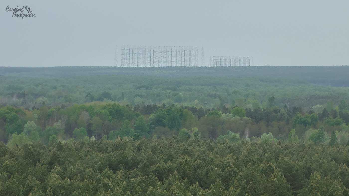 Image is taken from the top of a tower block in Pripyat. It's of a plain sky and treescape, with a small, barely distinguishable series of metal towers in the distant mist.