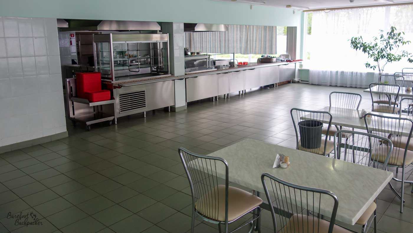 Inside the canteen at the Chernobyl Power Plant. It's very 'clean' and 'functional', with bare metallic serving stations and bland tables with ribbed chairs.