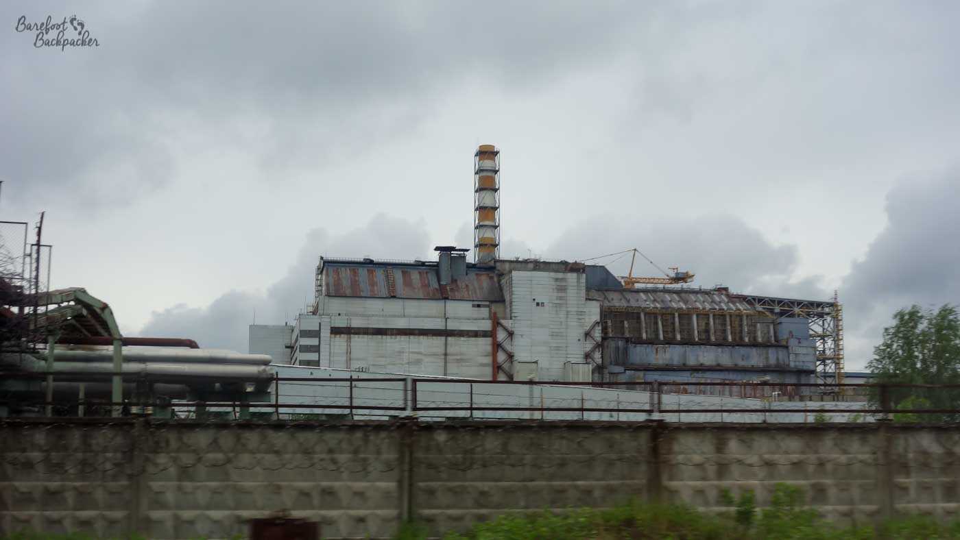 Grey and foreboding structure that is the Chernobyl Power Plant's nuclear reactor – long and dirty-white with a chimney.
