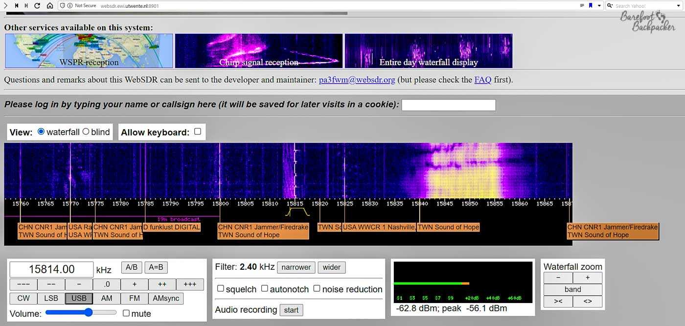 Screenshot of the University of Twente radio website. The main part of the screen is a waterfall-style display that has the frequency along the bottom, and lines of differing colours and widths depending on the strength and type of the signal on that frequency (most of the waterfall is plain dark blue or black indicating no signal is being received). Along the bottom, at the frequency axis, there are boxes at several points that tell you if something normally operates there, and other particular notes. For example, a couple of boxes say 'CHN CNR1 Jammer/Firedrake' alongside ''TWN Sound of Hope', and this is matched by purple and yellow lines in the waterfall. The screenshot also displays other functions you can use, such as the box to insert a frequency of your choice, and several technical options designed to hone your listening experience. The frequency being listened to is 15814 kHz USB, which has no box but at the time of screenshot (approx 12:24 UTC), there's a solid white line on the waterfall. This is indicative of a digital transmission – in fact a Russian Numbers Station.