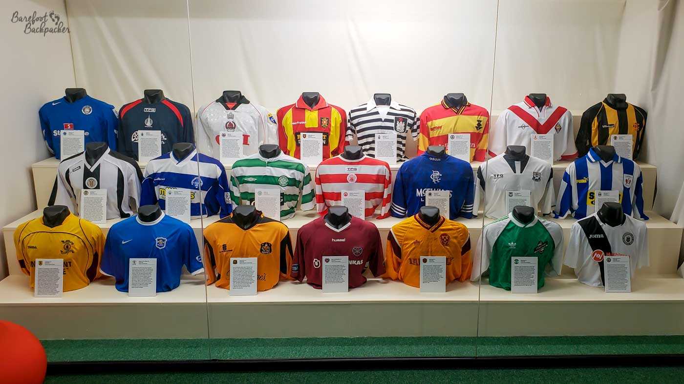 Behind a perspex screen are twenty-two different football shirts laid out in three rows.