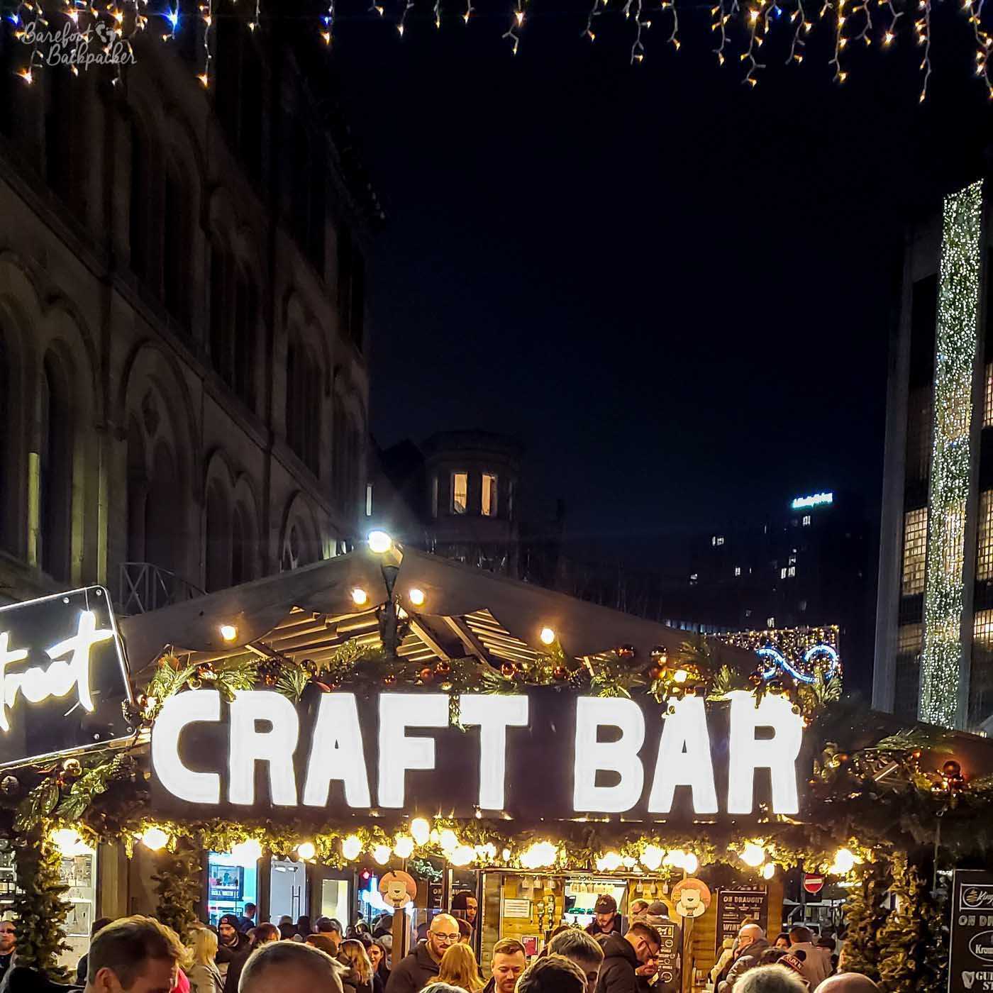 A shot taken at night, showing a pop-up cabin in a city street, King Street Craft Bar in bright lights. The place seems quite crowded.