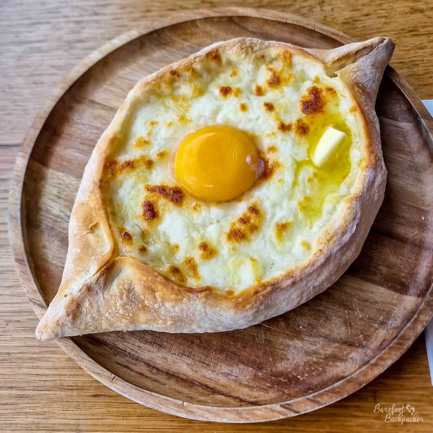 A picture of a roughly circular piece of bread, covered with cheese and an egg.