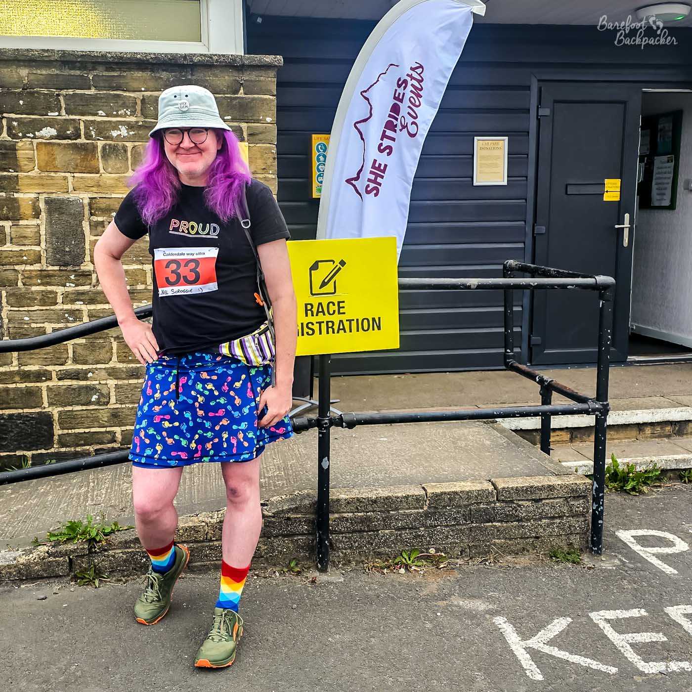 A person with purple hair and glasses wearing a black shirt that says 