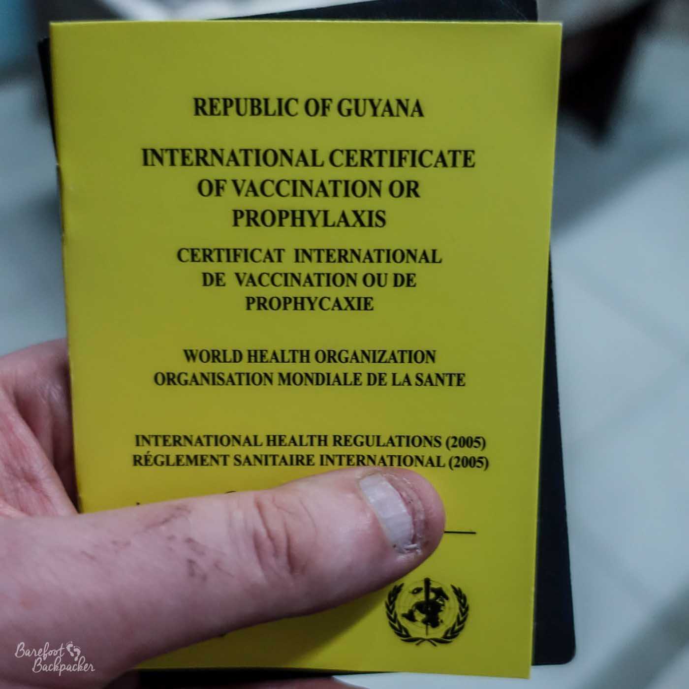 Close-up of the front of a Yellow Fever certificate – a small card with a brief description of what it is and who issued it, in English and French.