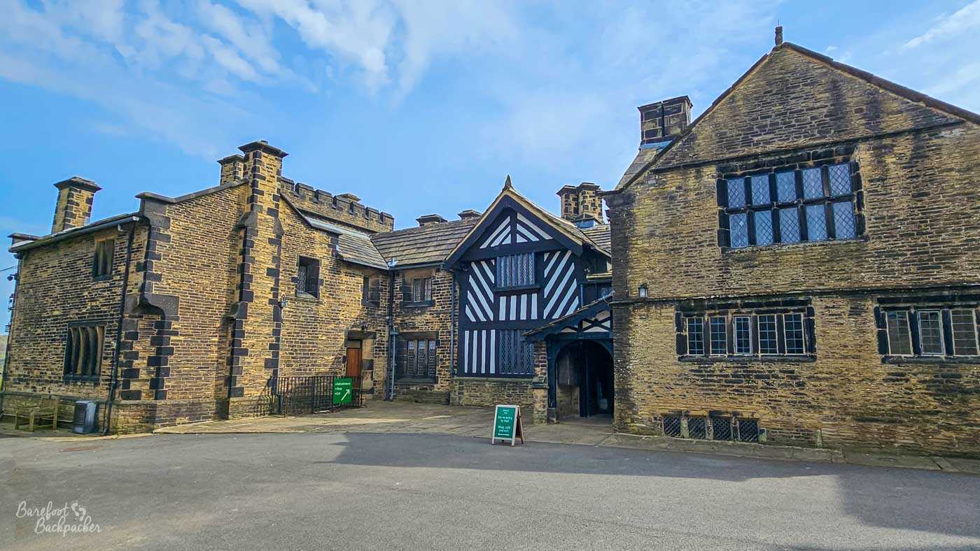 The rear courtyard of Shibden Hall is surrounded by historic stone buildings, timber-framed sections and mullioned windows, illustrating the hall's varied architectural styles.