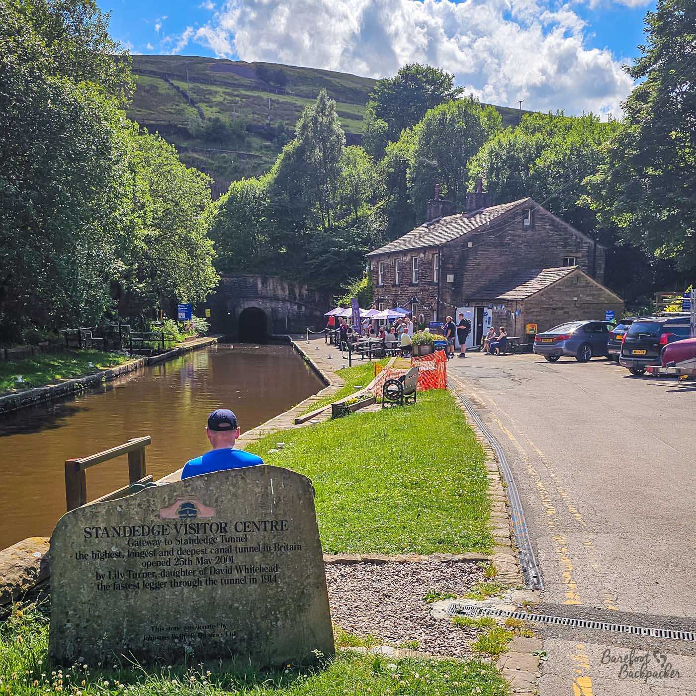 The entrance to Standedge Tunnel on the Huddersfield Narrow Canal sits beyond the visitor centre, with canal boats, waterside cafés and wooded hills surrounding Britain's longest canal tunnel.