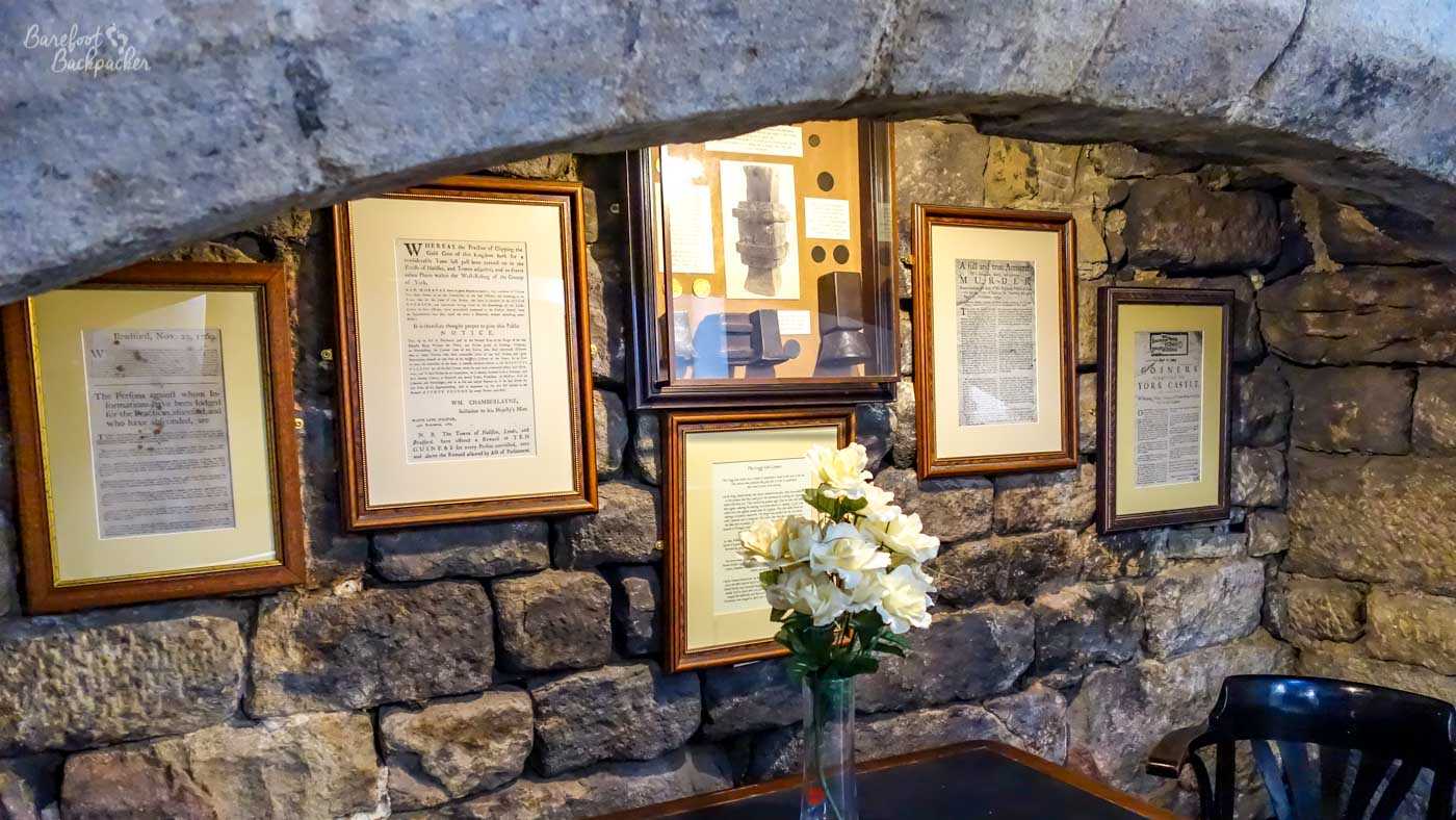 Framed newspaper reports and artefacts displayed on a stone wall inside the White Lion Inn.