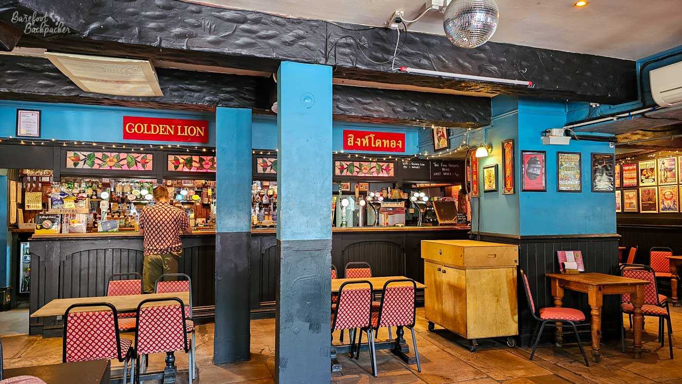 A customer stands at the long wooden bar beneath illuminated